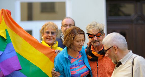Fünf Senioren mit einer großen bunten Fahne | © Caritas