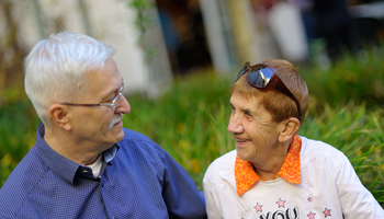Zwei ältere Menschen lächeln sich an | © Caritas München und Oberbayern