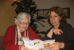 Pflegerin und ältere Dame sehen sich zusammen einen Flyer an | © Caritas München und Oberbayern